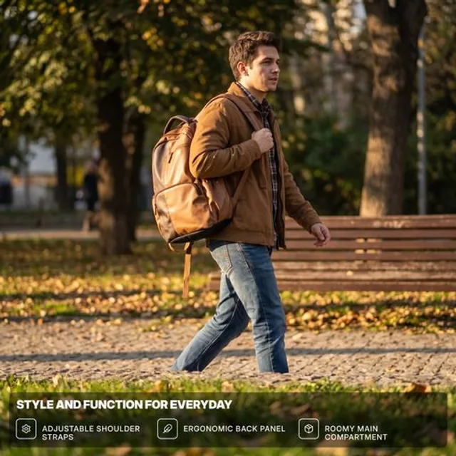 A man walking down a tree-lined street wearing a two-tone backpack